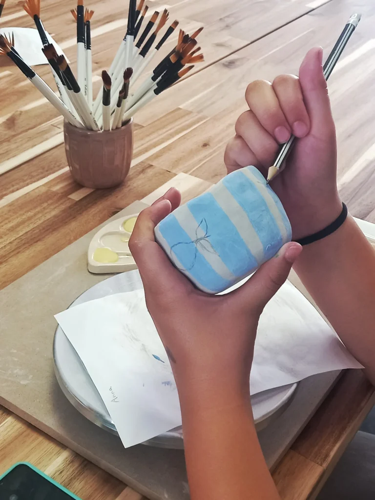 Manos pintando pieza de cerámica