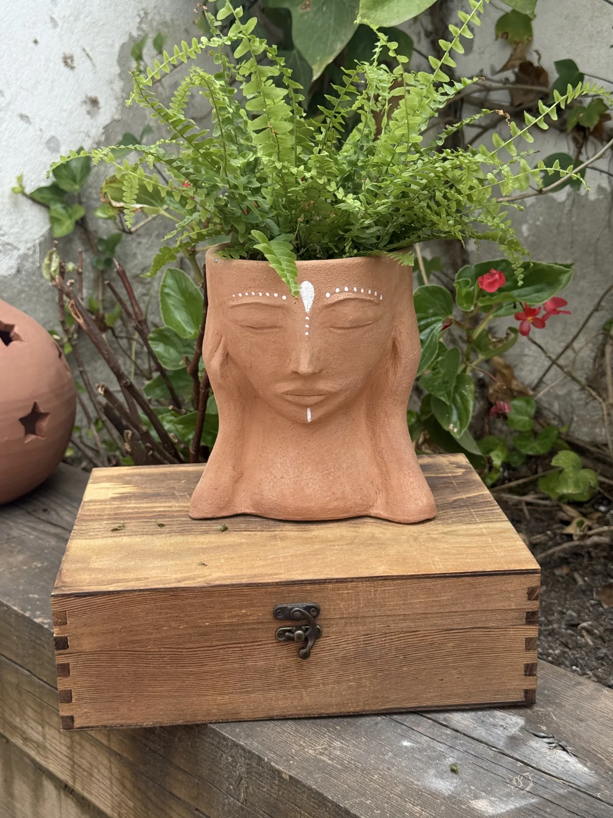 Busto de cerámica terracota con marcas blancas estilo precolombino y planta en la cabeza